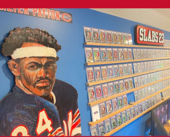 Hand-painted Walter Payton mural beside a wall of PSA-graded slabs at the Slabs 23 office